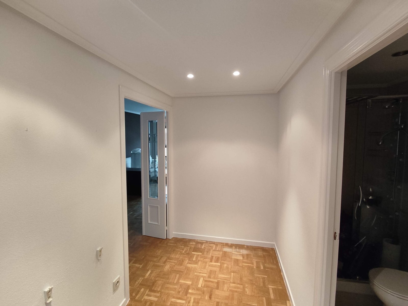 Pasillo con puertas, suelo de madera, iluminación LED