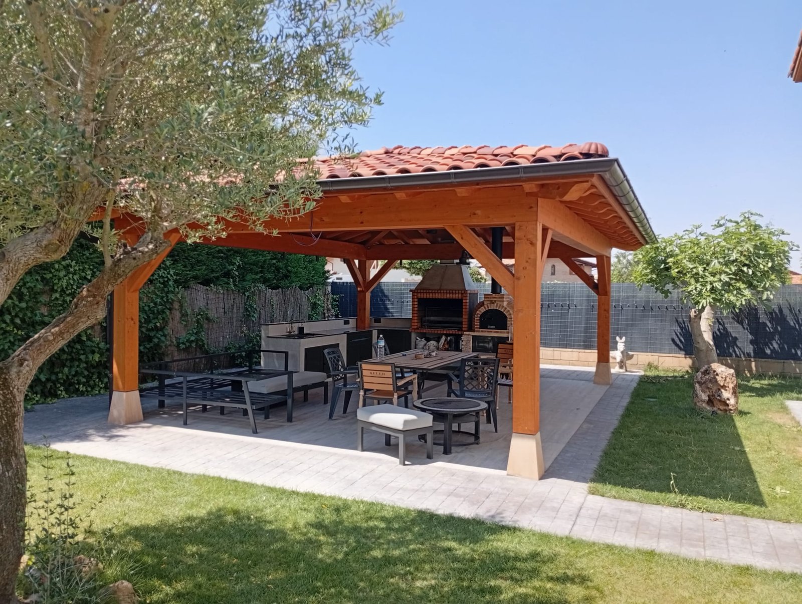 Pérgola de madera con barbacoa en jardín soleado