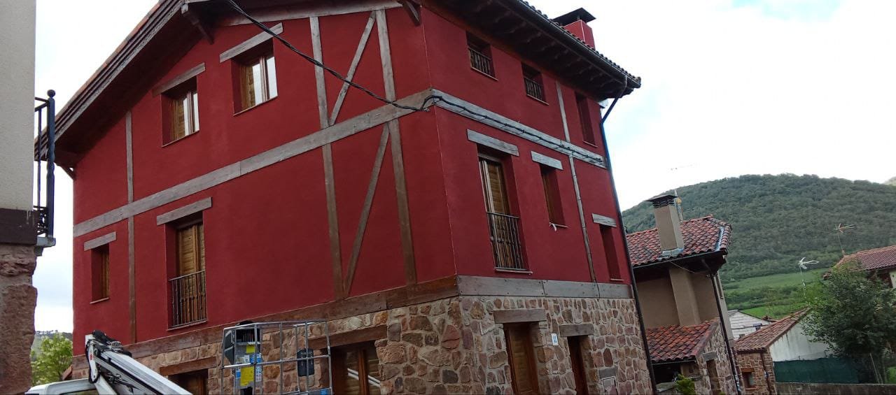 Casa roja de piedra en entorno rural.