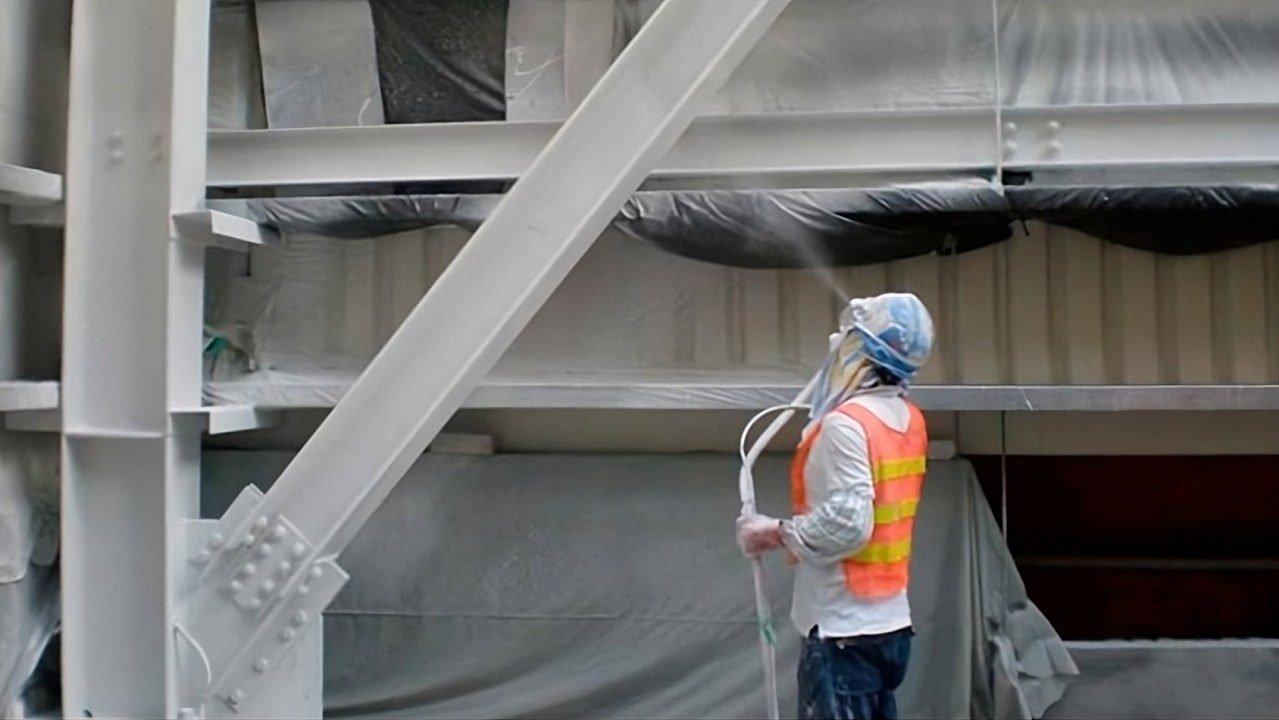 Trabajador pintando estructura metálica con spray