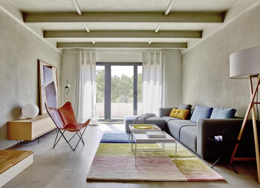 Salón moderno con sofá gris y luz natural.