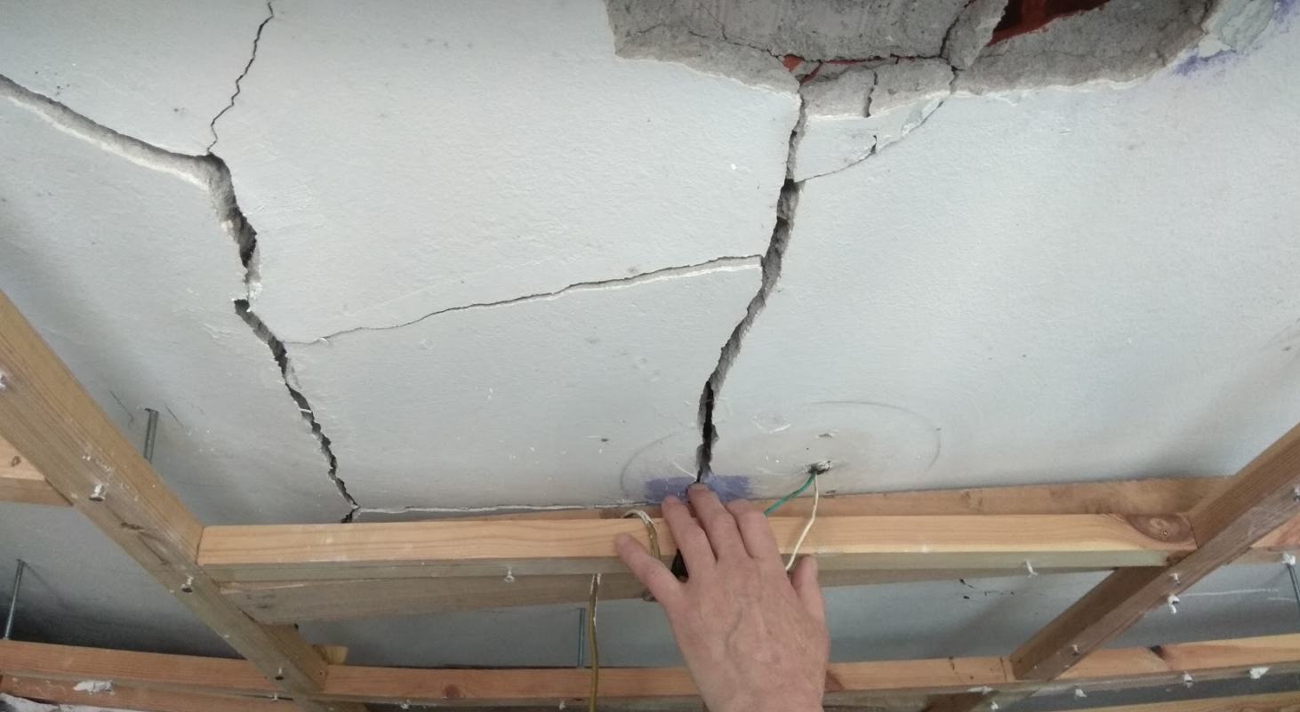 Grietas en el techo con mano examinando