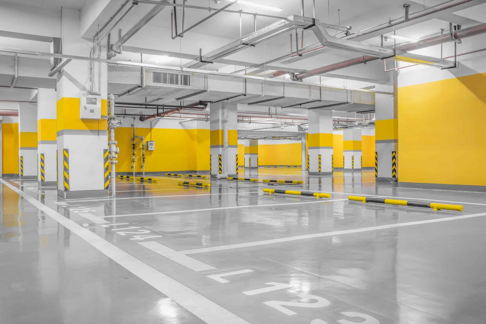 Aparcamiento subterráneo vacío con líneas amarillas.