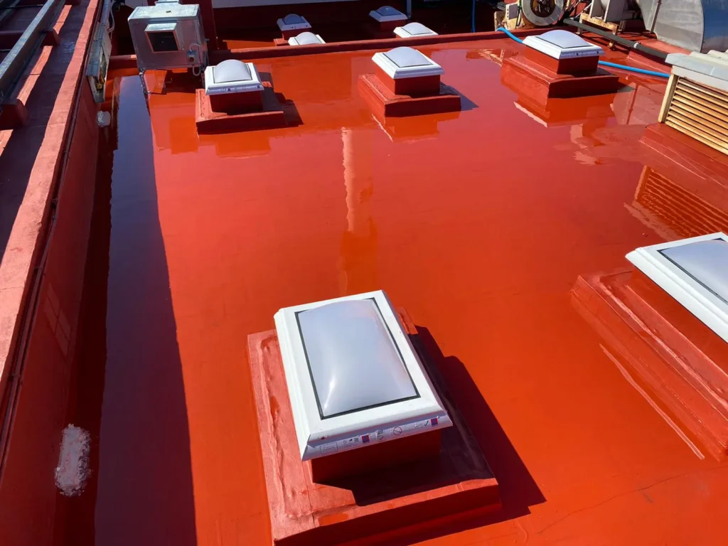 Techo rojo impermeabilizado con claraboyas blancas.